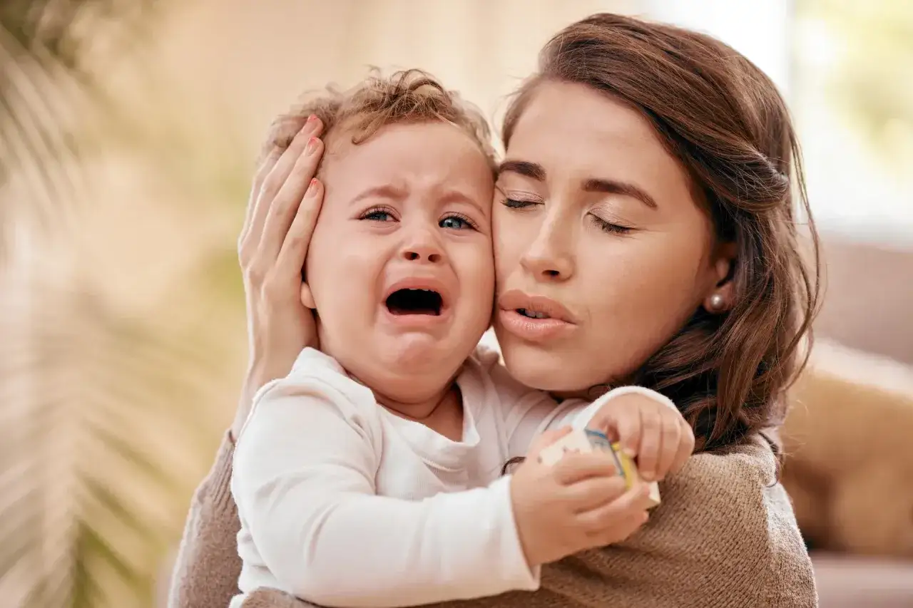 zmęczona mama z niemowlakiem na rękach uśmiecha się